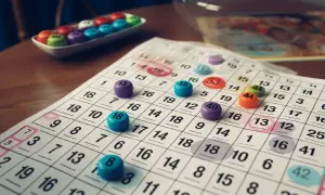 Kolorowe żetony bingo leżą na kartach do gry z zaznaczonymi liczbami.