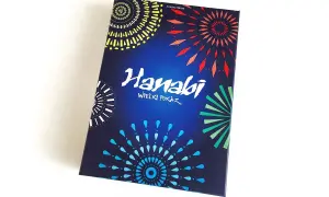 Pudełko gry karcianej Hanabi z kolorowymi fajerwerkami na ciemnoniebieskim tle.