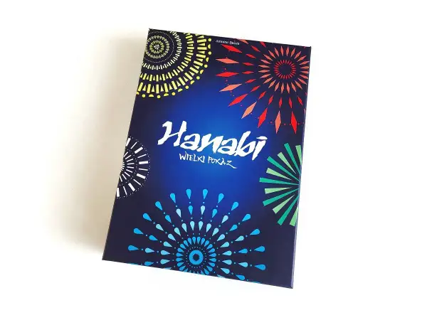 Pudełko gry karcianej Hanabi z kolorowymi fajerwerkami na ciemnoniebieskim tle.